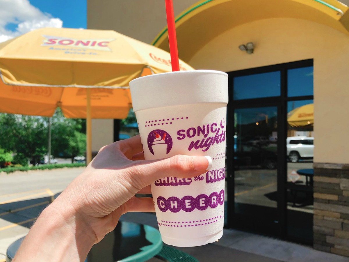 hand holding cup in front of store