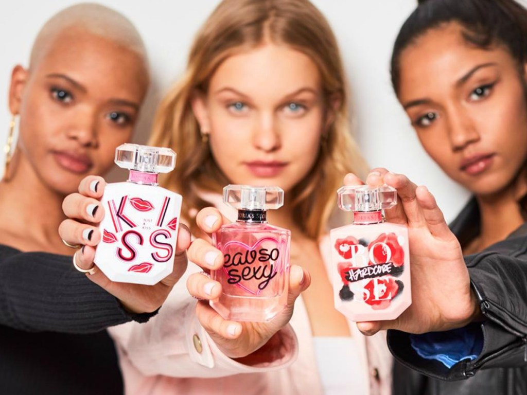 three women holding three bottles of perfume