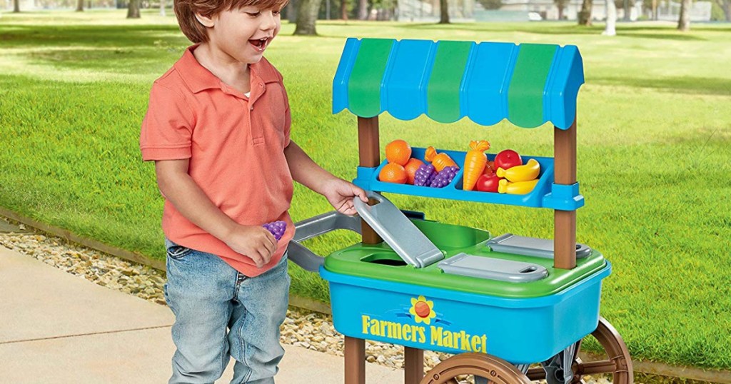 little boy playing with plastic cart and food toys