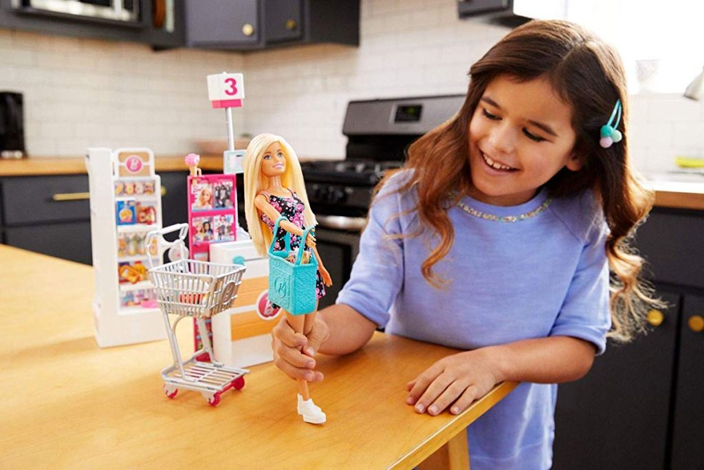 girl playing with Barbie Supermarket Playset