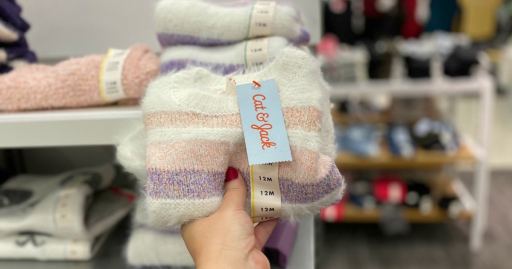 Woman holding Cat & Jack striped sweater in Target store