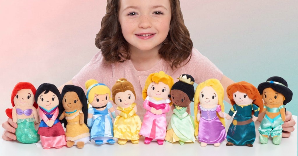 Young girl with a Disney Princess Plush Dolls collection on table top