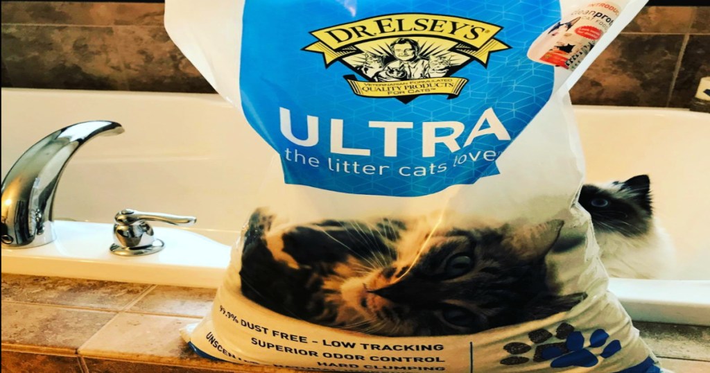 Dr. Elsey’s Premium Clumping Cat Litter Bag on the side of a bath tub with white cat in the tub