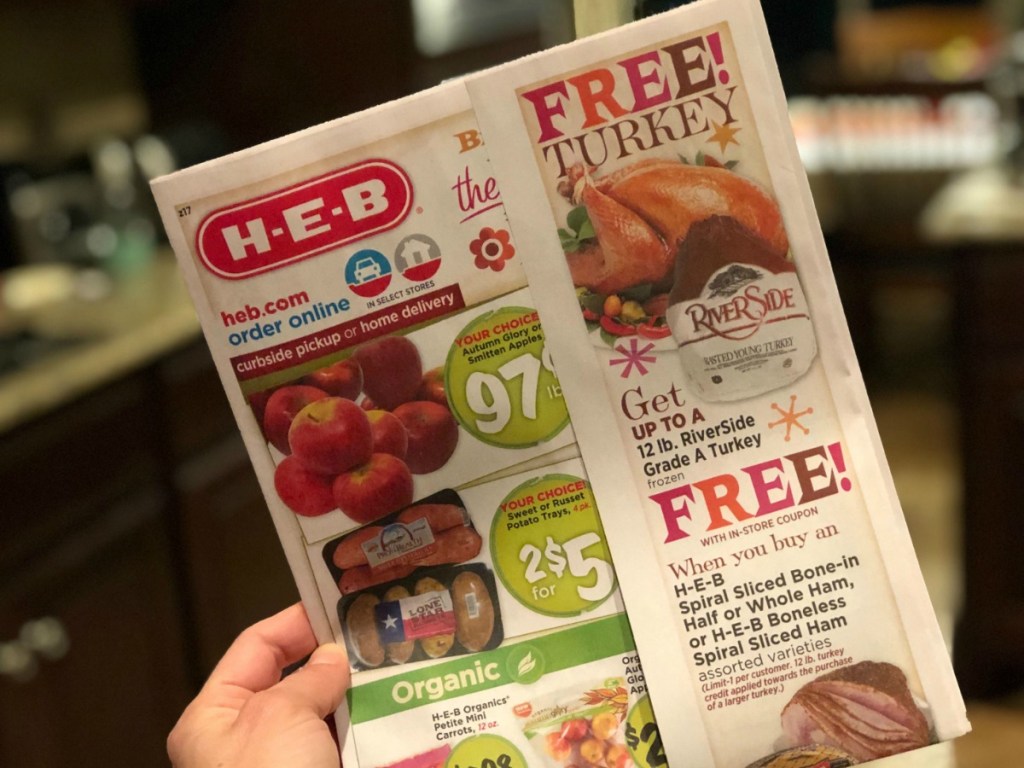 woman holding an HEB ad for a free turkey