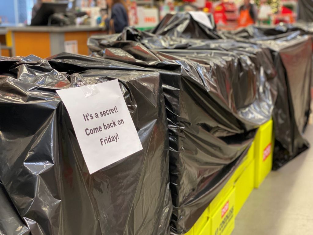 boxes covered with black tarps and a sign that says to check back on Black Friday