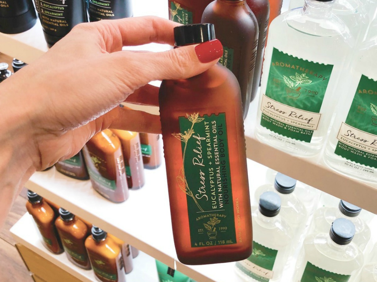 Stress Relief Body Oil in bottle in hand in front of in-store display at Bath & Body Works