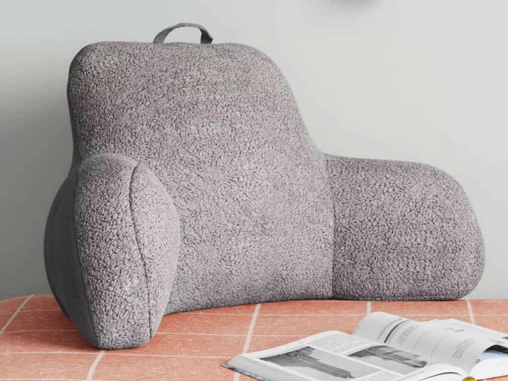 Gray sherpa bedrest pillow on coral bedspread in bedroom