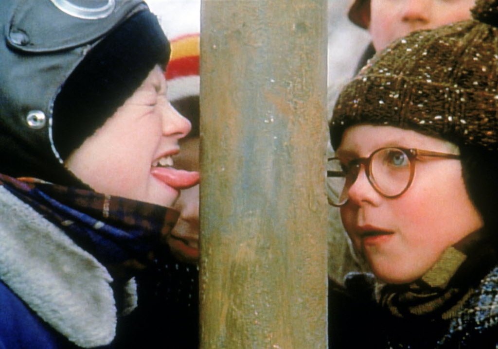 two boys standing next to pole with tongue sticking on it
