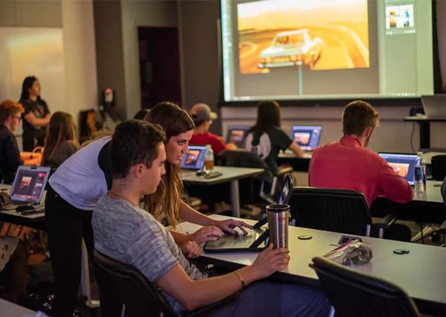 woman assisting student using laptop