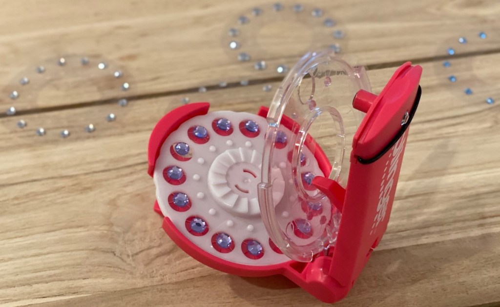 hot pink blinger toy sitting on wood table with gems