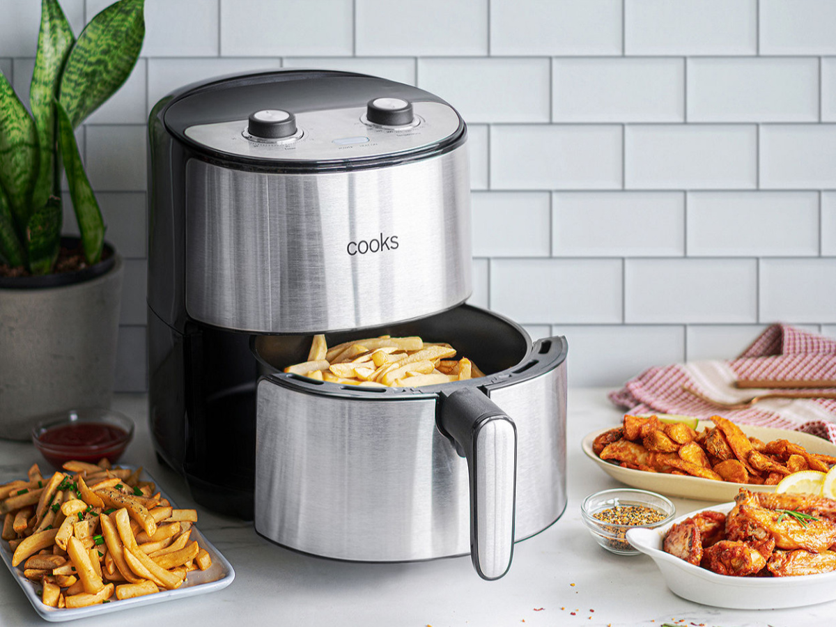 stainless steel cooks air fryer with basket out showing fries and fried foods in background