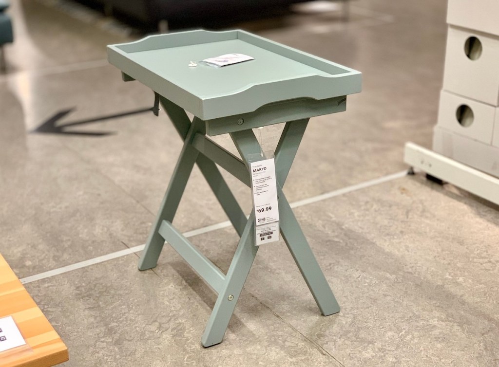 ikea sage green tray table sitting in middle of concrete floor 