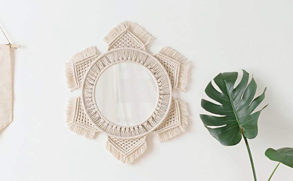 Macrame mirror on wall next to plant