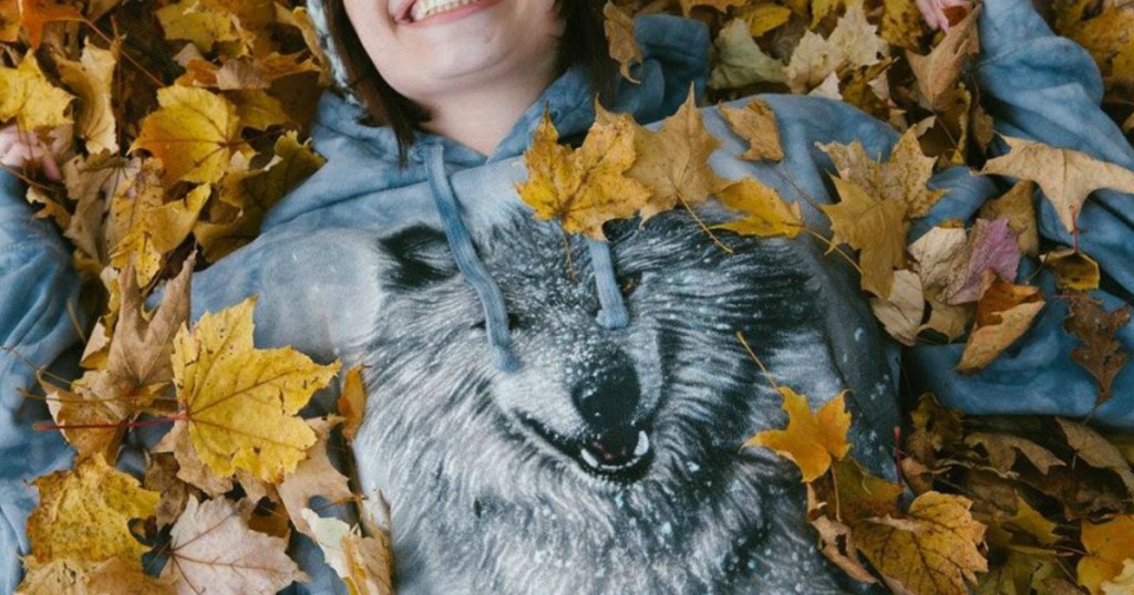 woman laying in leaves with wolf sweatshirt 