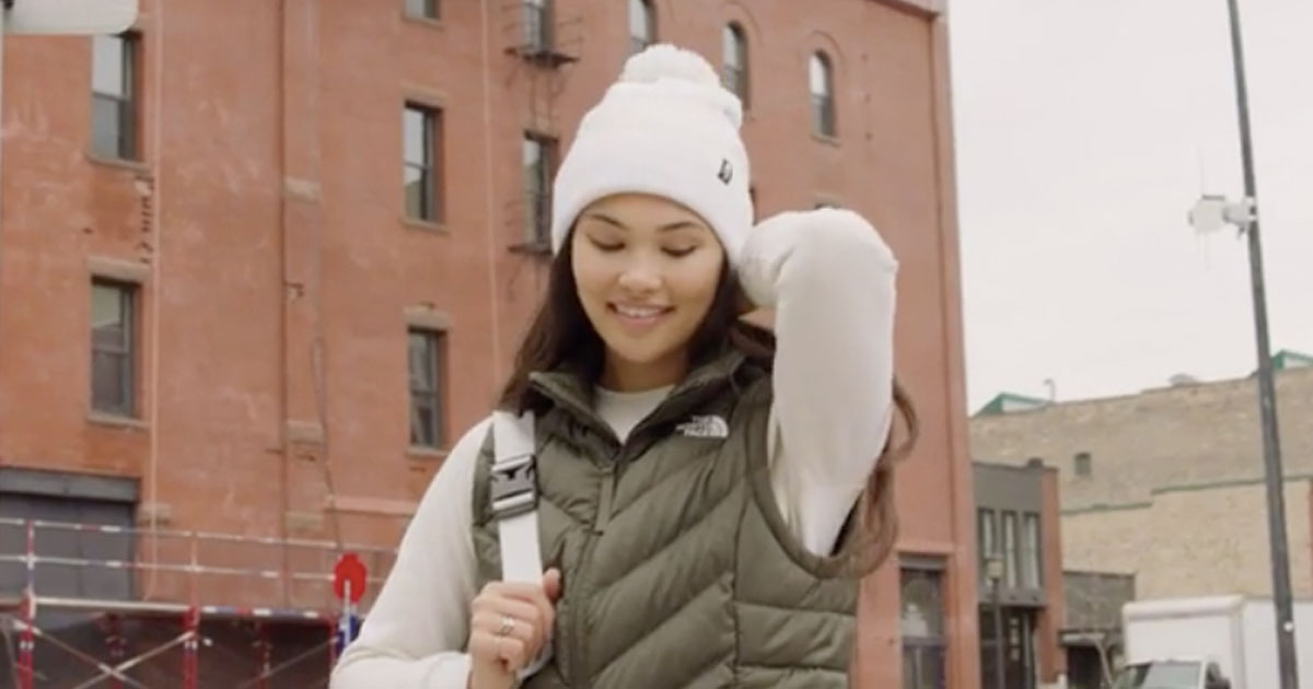 Woman standing outside of a building in the cold wearing a The North Face vest