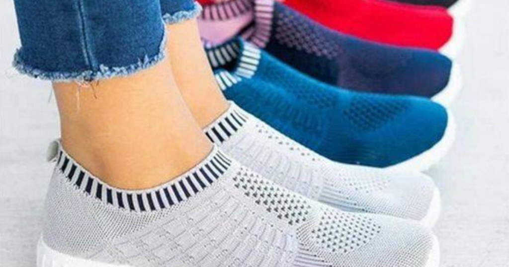legs in pair of shoes standing by other pairs of shoes