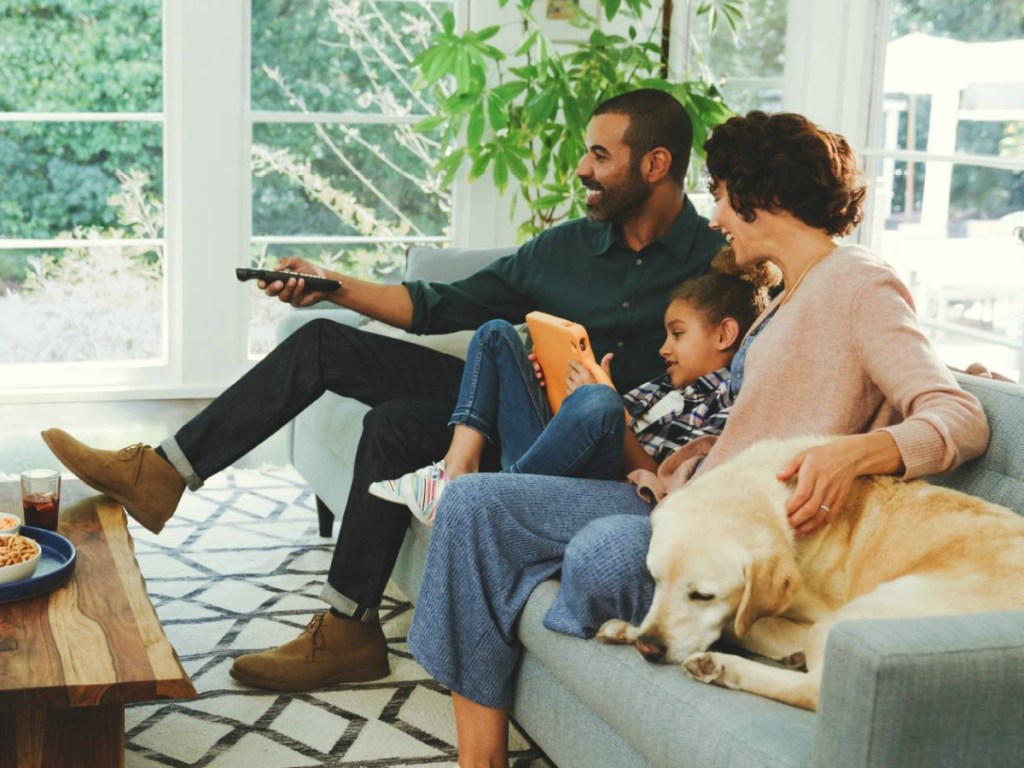 family watching tv sitting on couch with dog