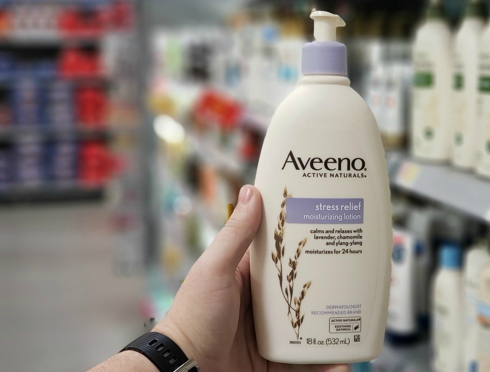 Hand holding Aveeno Moisturizing Lotion