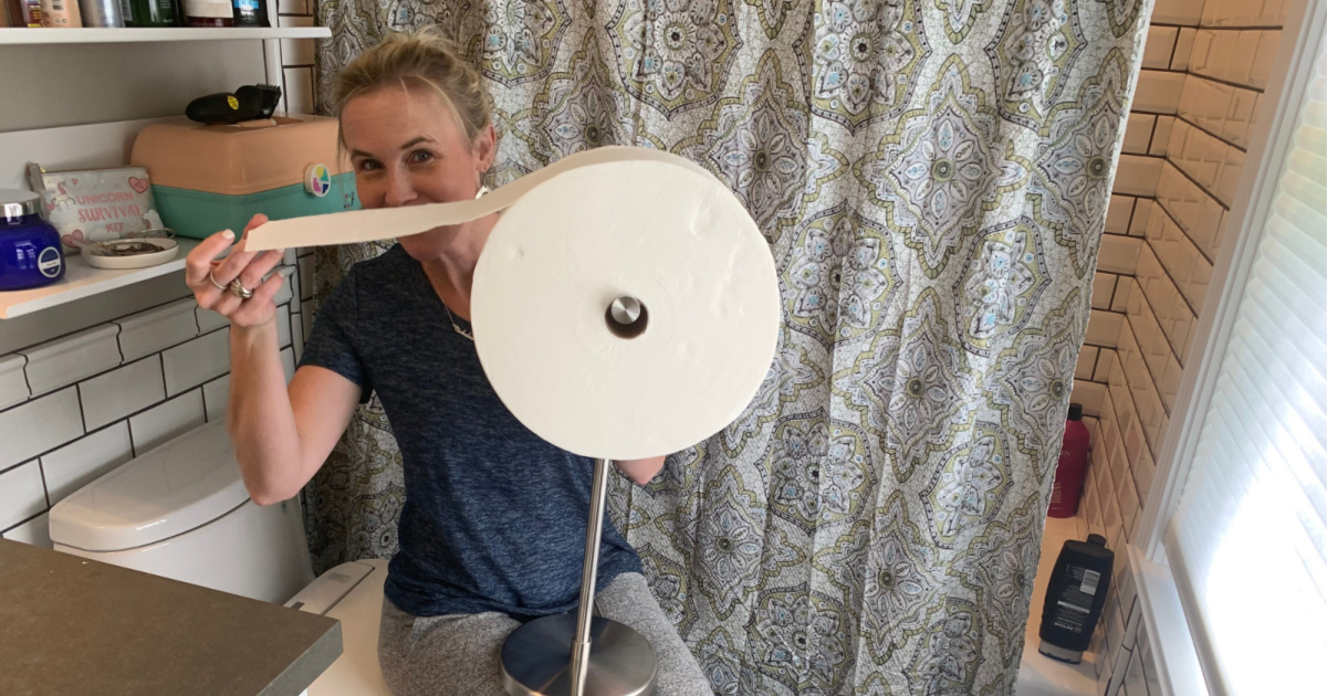 woman holding charmin forever roll in the bathroom on the toilet