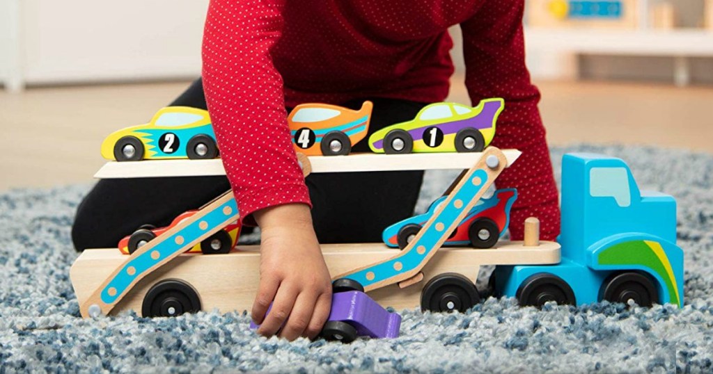 Girl playing with a Melissa & Doug race car carrier playset