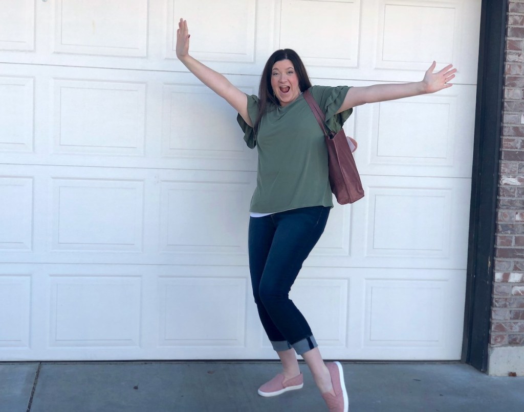 woman with hands in the air standing in front of white garage door