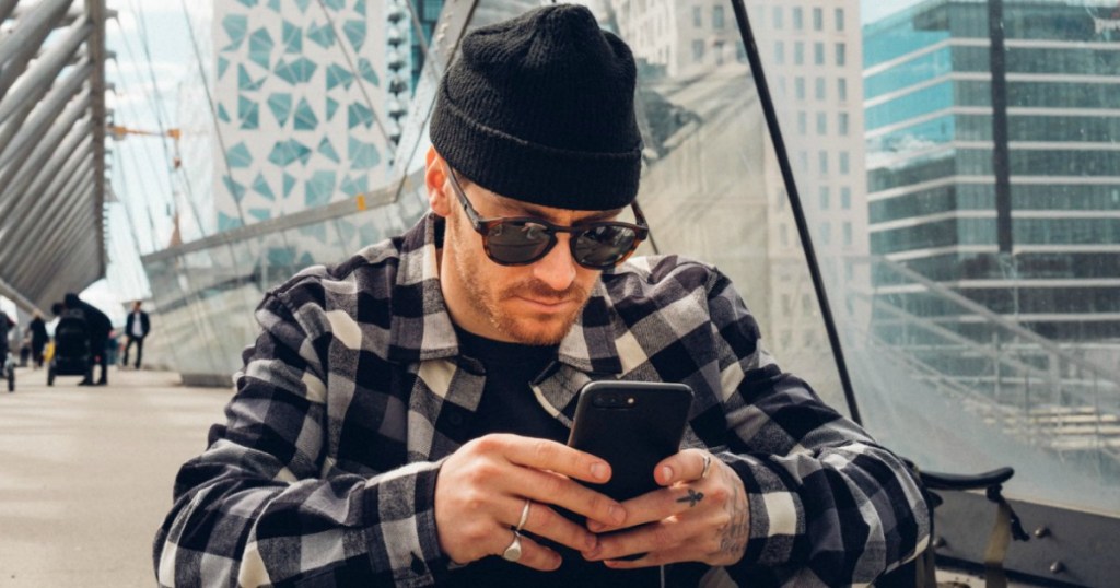 man in sunglasses and a beanie looking at his phone