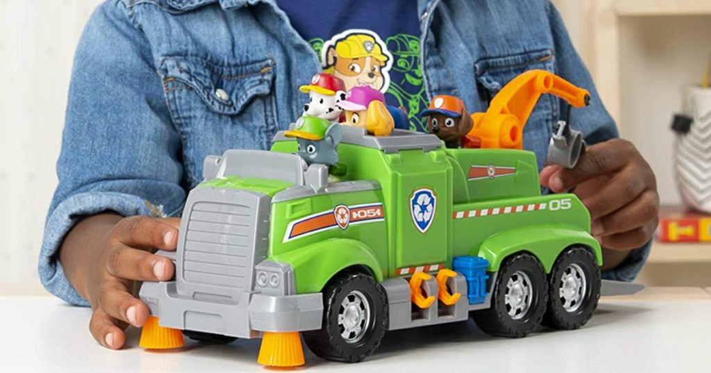 boy playing with a Paw Patrol green rescue truck