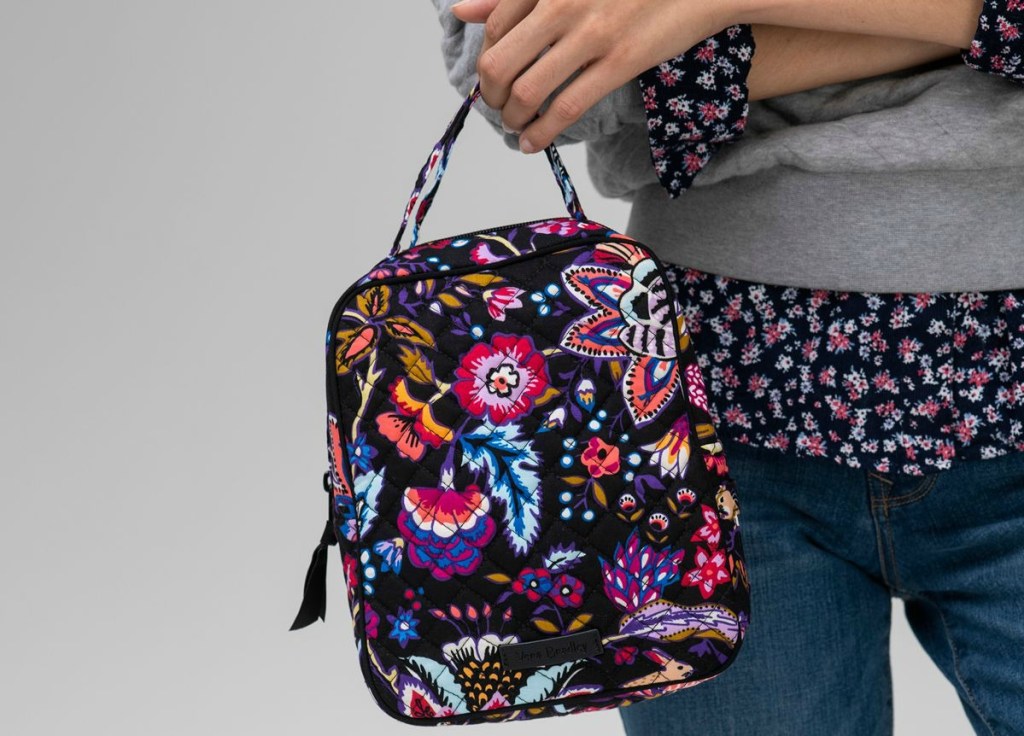 woman holding a floral multicolored lunchbag