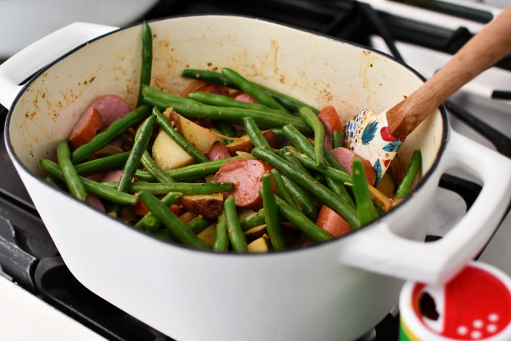 adding green beans and potatoes to dutch oven