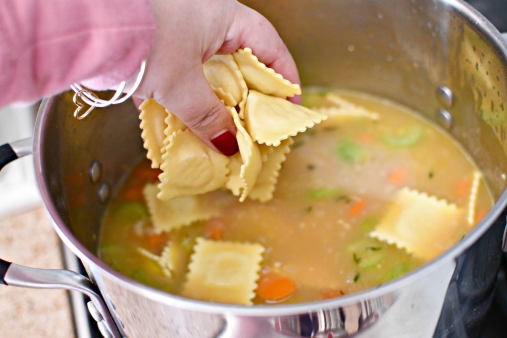 adding raviolis to creamy ravioli soup