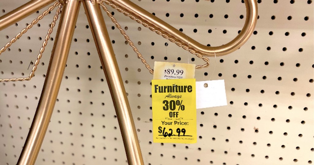 yellow furniture sale tag hanging from brass metal on store shelf 