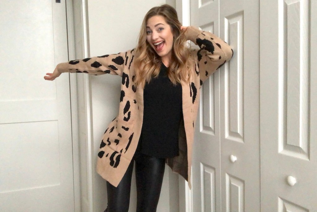 woman smiling and happy wearing beige and leopard cardigan with black shirt and leggings