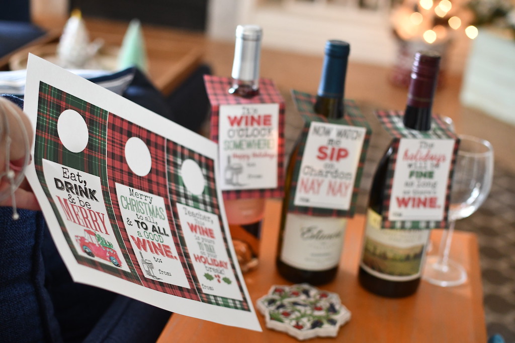 holding printable Christmas wine tags with wine bottles in the background