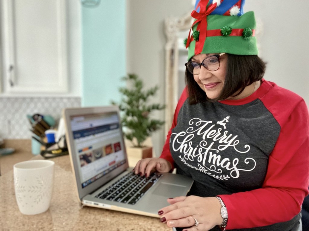 woman dressed for Christmas looking at laptop for cyber monday deals