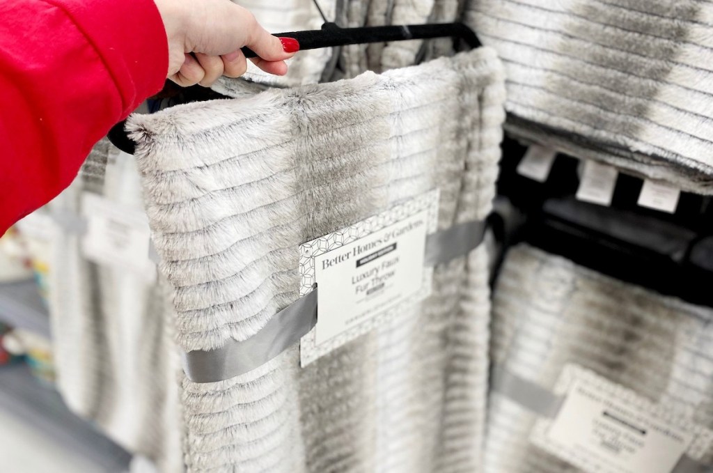 hand holding a gray and white faux fur throw blanket in packaging