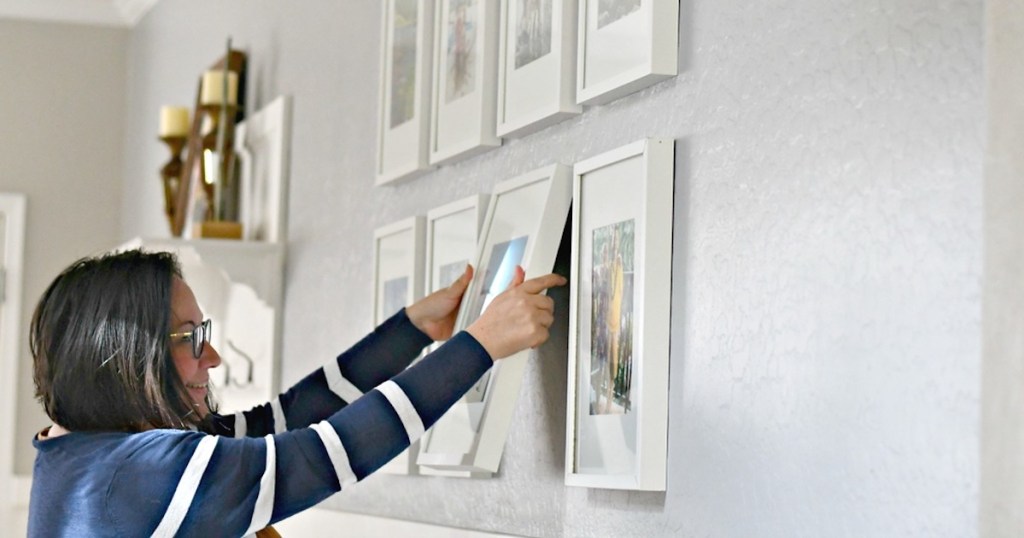 woman holding white picture frame on gallery wall