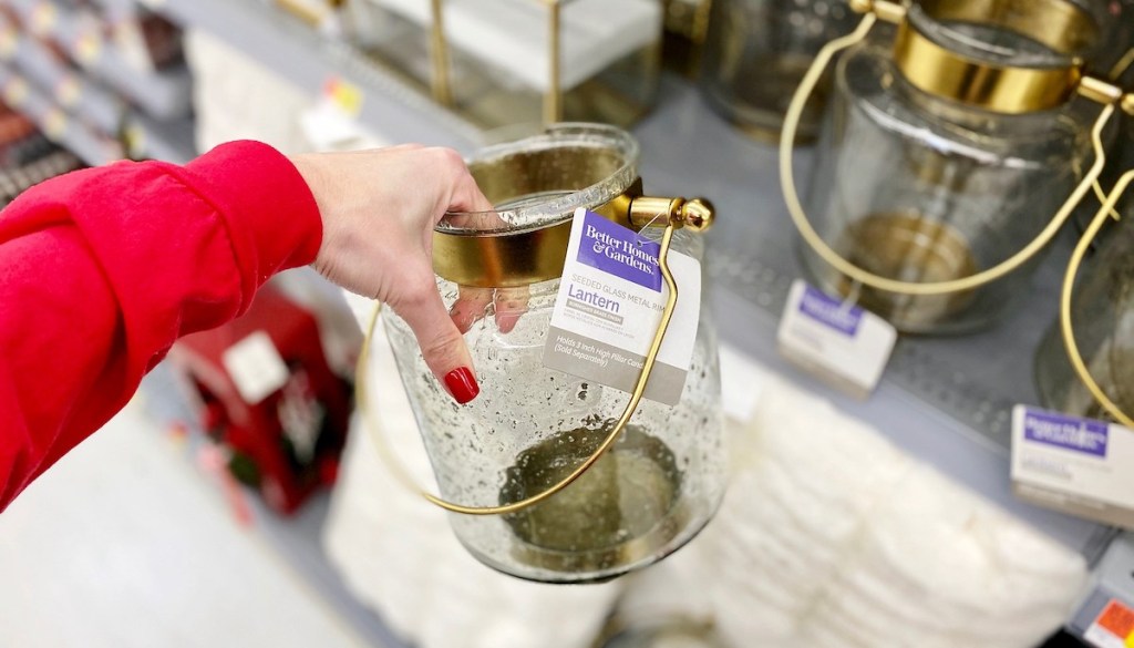 hand holding clear glass and brass lantern 