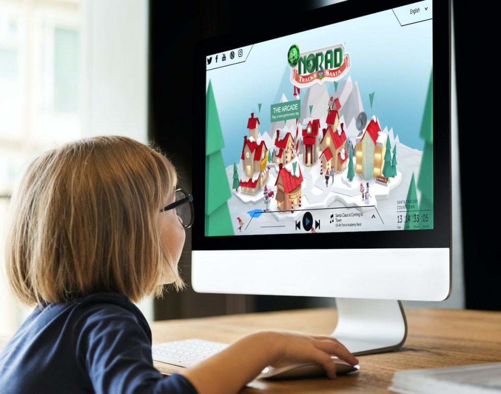 little girl sitting in front of the norad santa tracker virtual north pole on computer screen