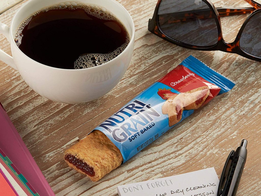 nutri-grain bar on table with coffee cup and sunglasses beside it