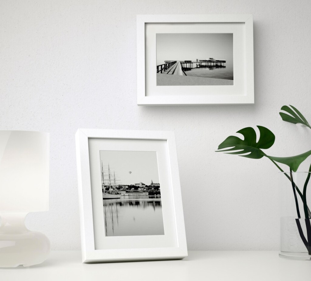 two white picture frames on white desk and wall