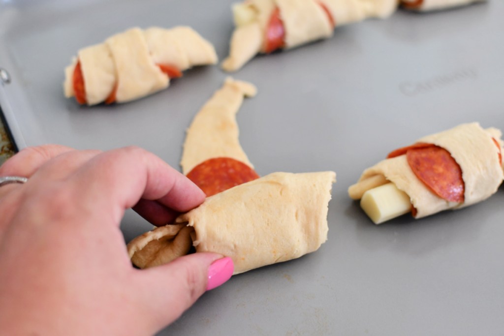 rolling up a crescent roll with pepperoni and cheese