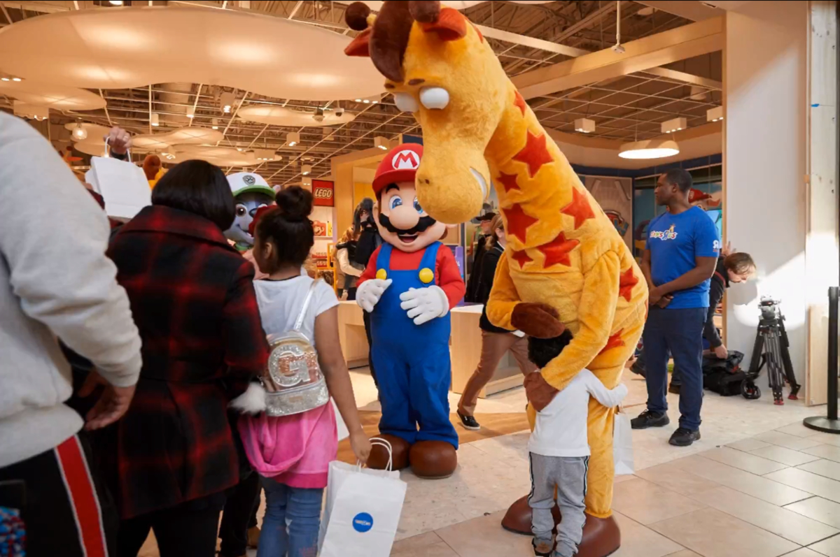 Geoffrey the Giraffe hugging a child