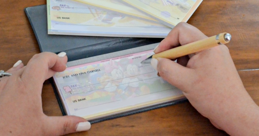 Woman filling out a check with a pen in her checking book