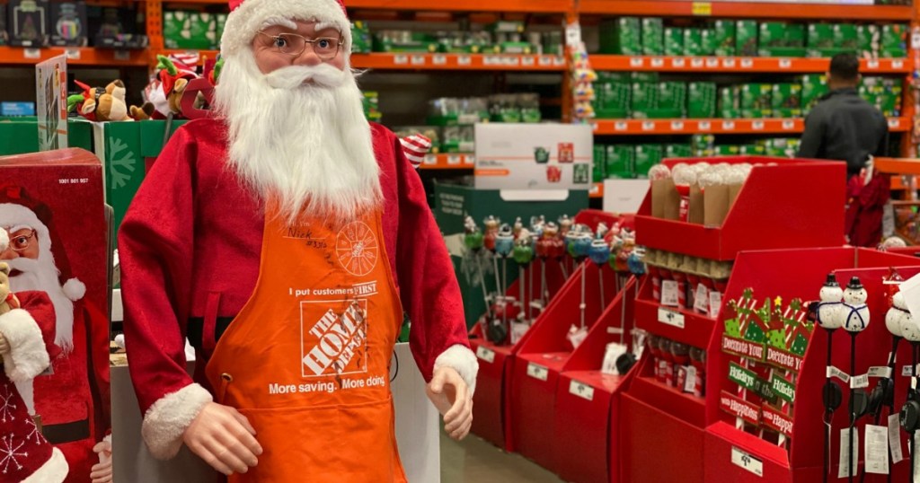 Santa near Christmas decorations wearing Home Depot apron