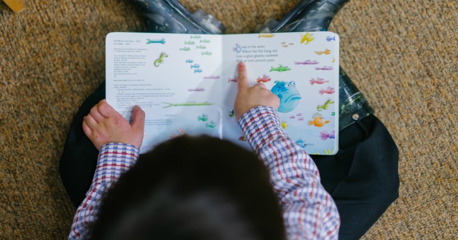 Kid reading board book and pointing to words
