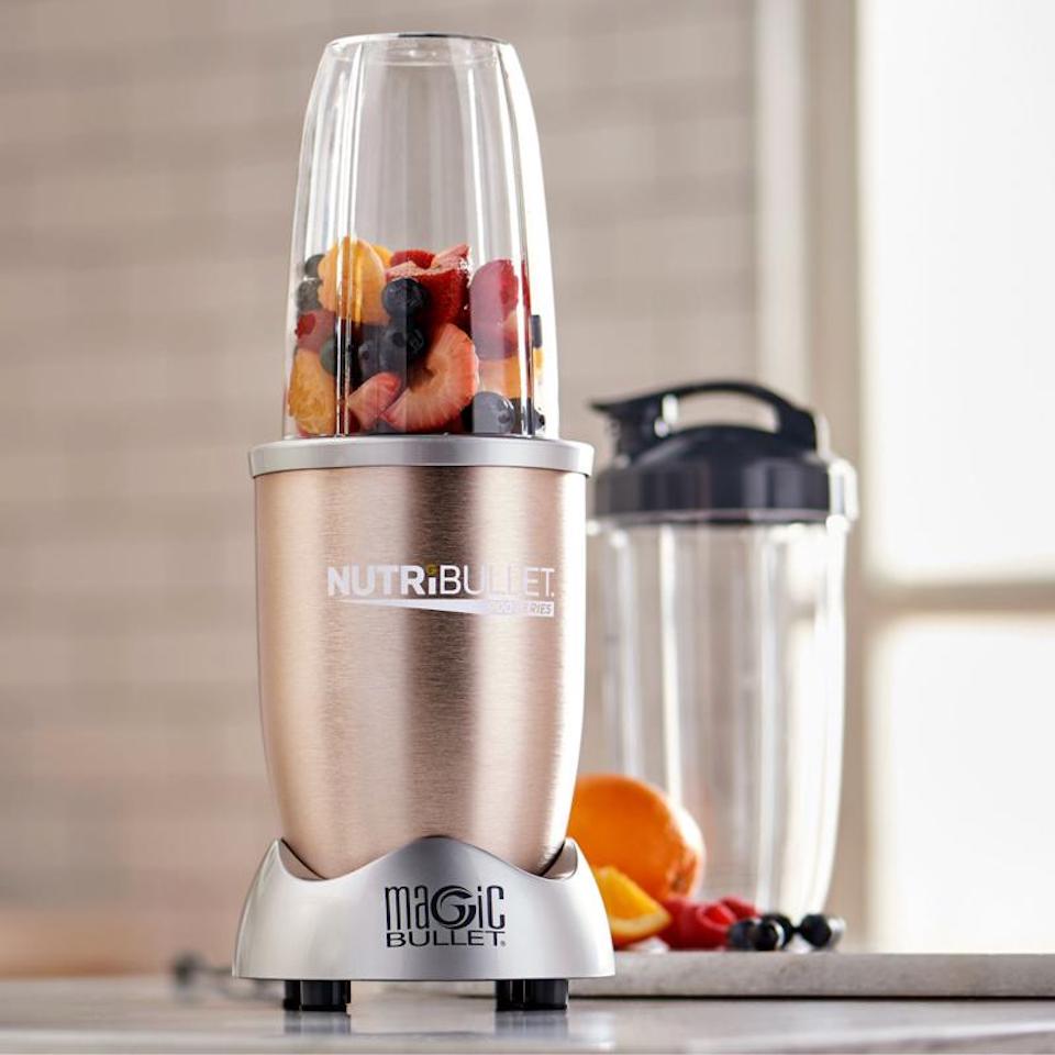 Nutribullet with fruit in it next to a cup