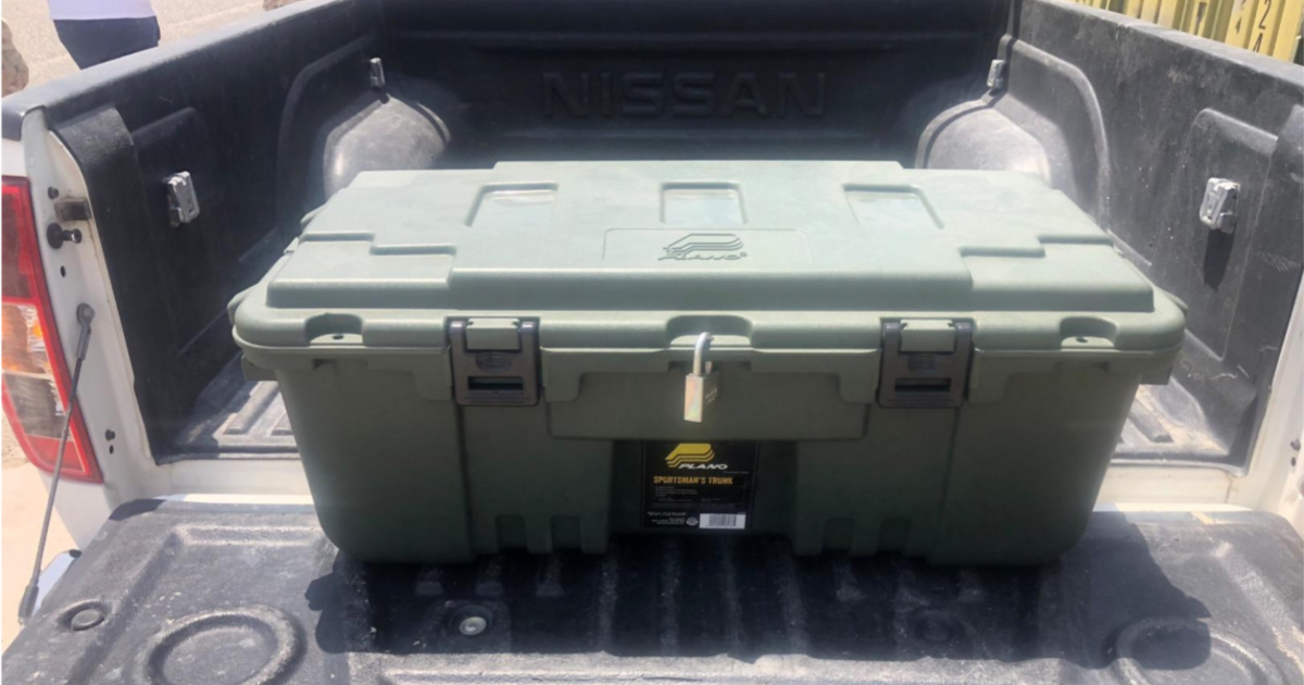 green trunk with padlock placed in back of truck on the tailgate 