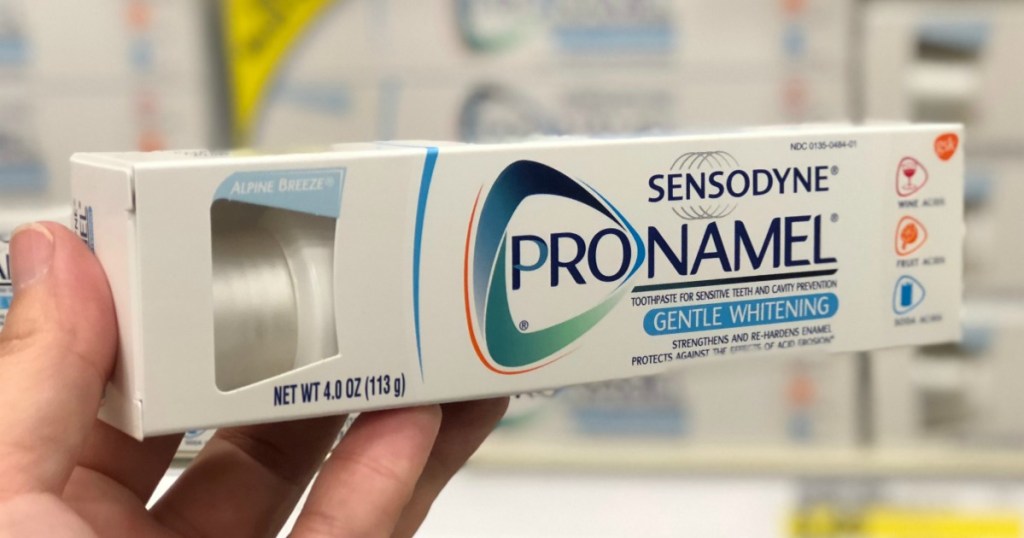 Sensodyne brand toothpaste in hand in-store in front of display