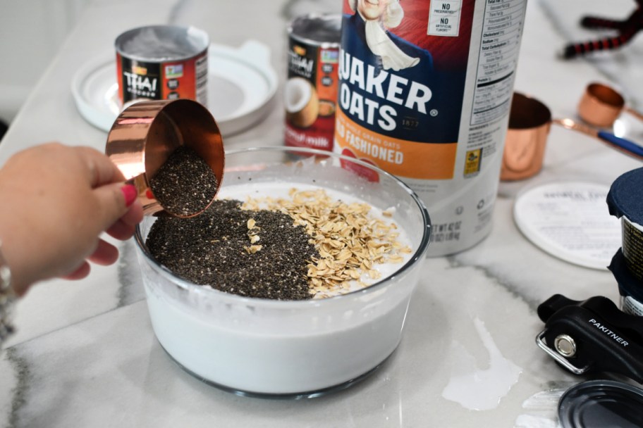 adding chia seeds and oats to a bowl with coconut milk