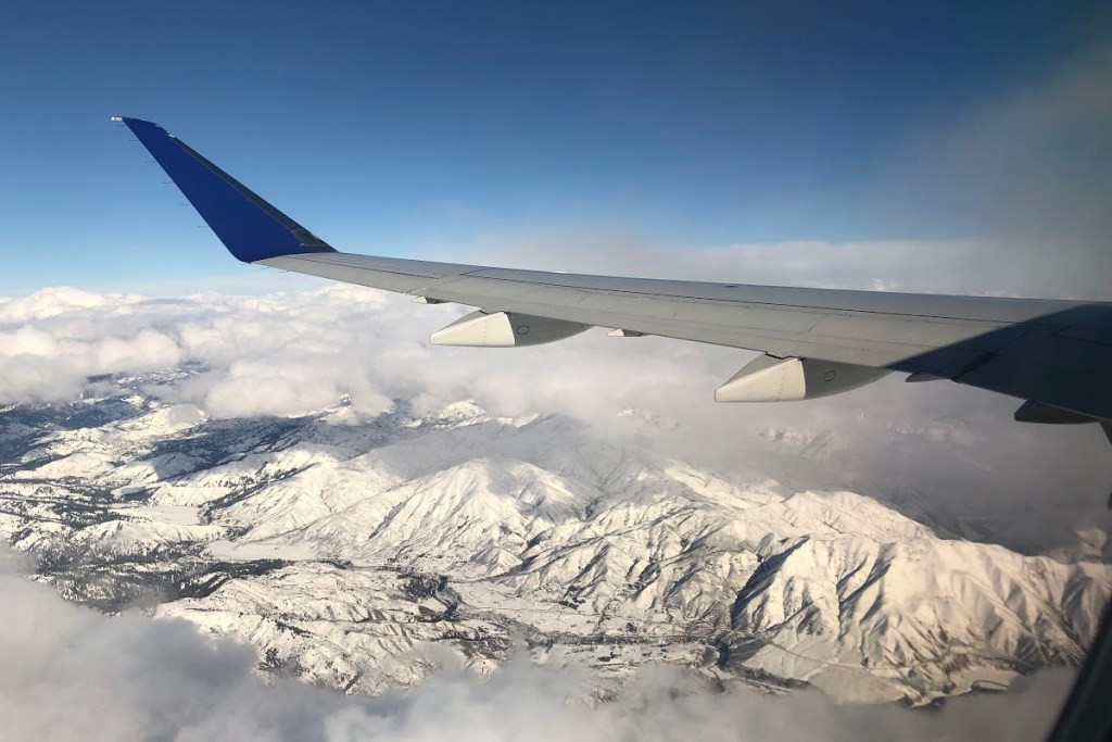 airplane wing over snowy mountains